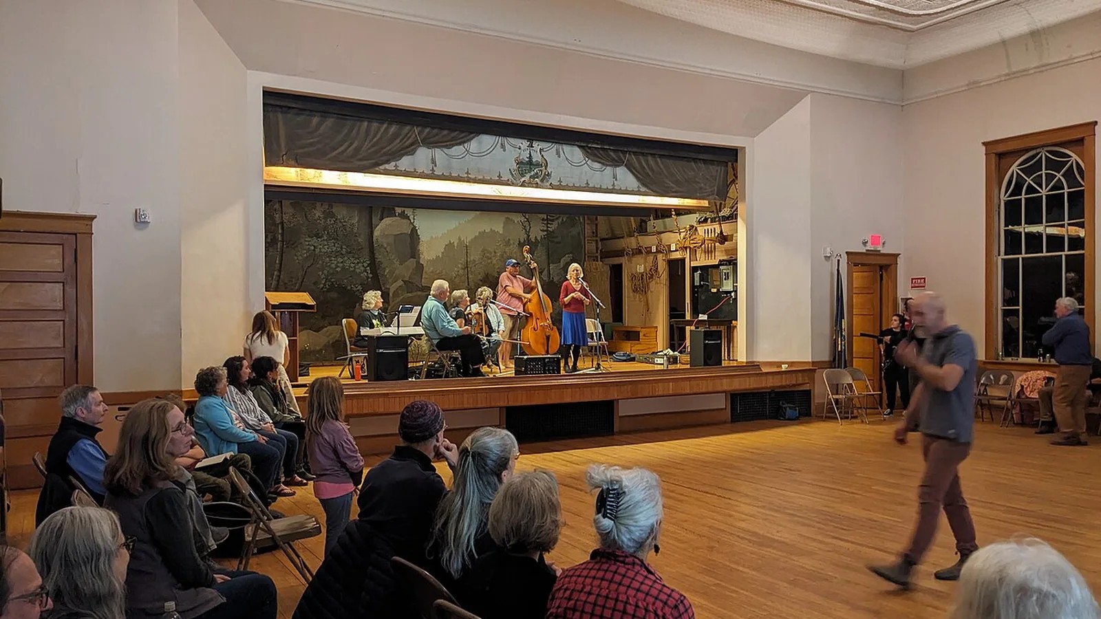 People gathering for a community square dance in a town hall